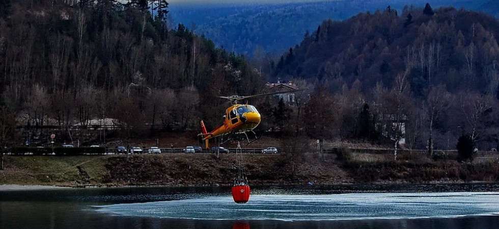 Il prelievo d' acqua di uno degli elicotteri Écureuil della Provincia impegnato nello spegnimento di un incendio sopra Biacesa (Foto Alberto Migliorini)