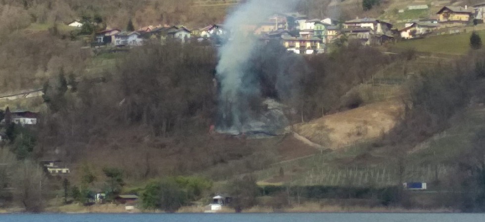 Svariati vigili del fuoco in azione per domare un incendio boschivo in zona impervia sopra la statale della Valsugana