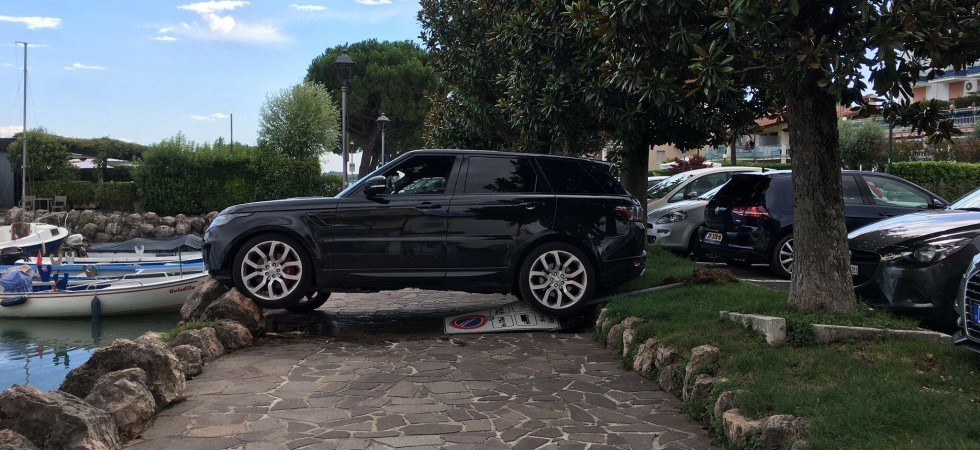 Sbaglia marcia e con il mega Suv abbatte il divieto e si incastra sui sassi frangiflutti