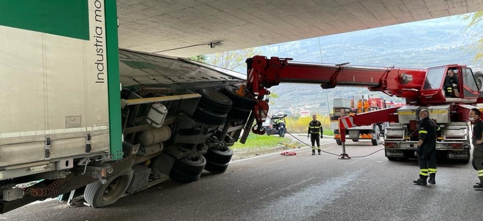 Agganciato con una gru il rimorchio torna in piedi sotto il cavalcavia: VIDEO e FOTO del difficile intervento dei pompieri