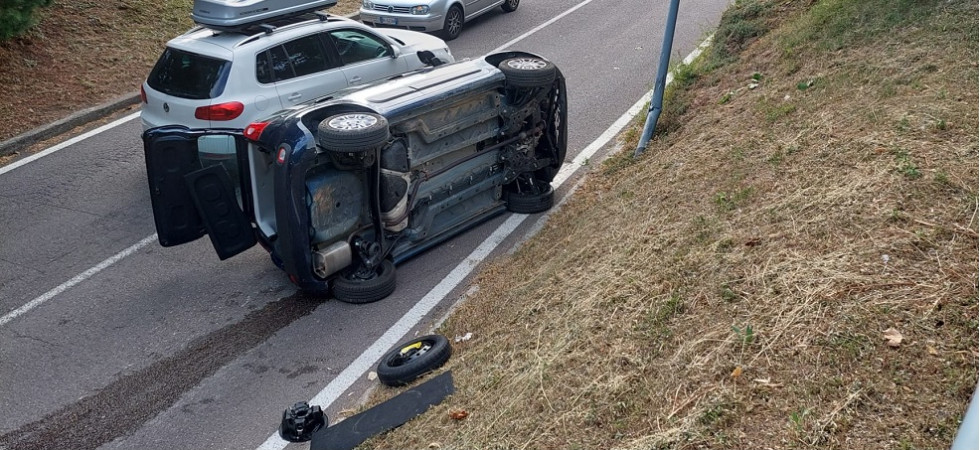 Un'auto si rovescia in mezzo alla strada, soccorritori in azione e traffico in tilt