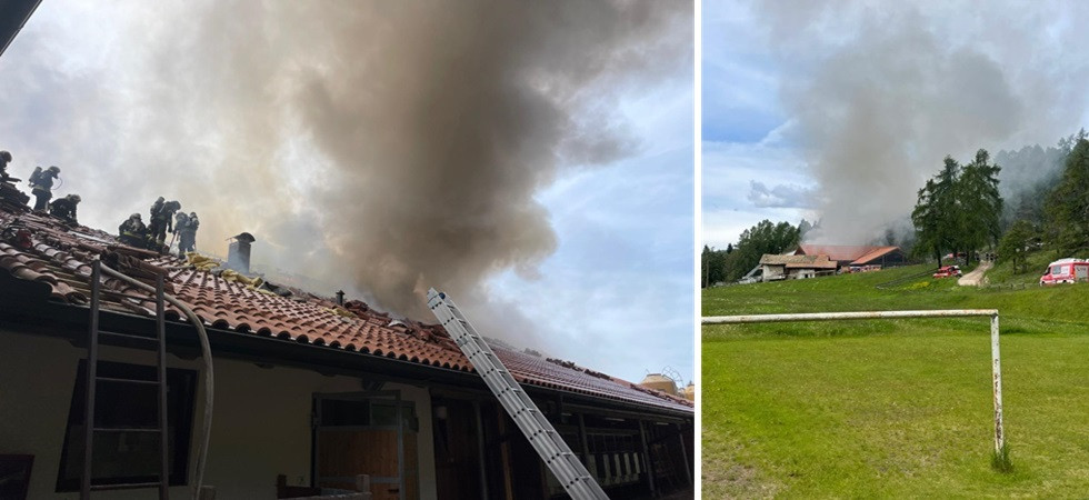 Fienile in fiamme e si alza un'alta colonna di fumo in cielo: vigili del fuoco in azione per domare il rogo