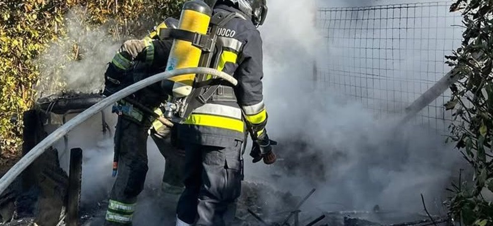 Le fiamme avvolgono una legnaia, vigili del fuoco in azione