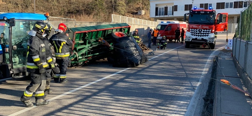 Il trattore si sbilancia, il rimorchio si rovescia e la legna finisce in strada