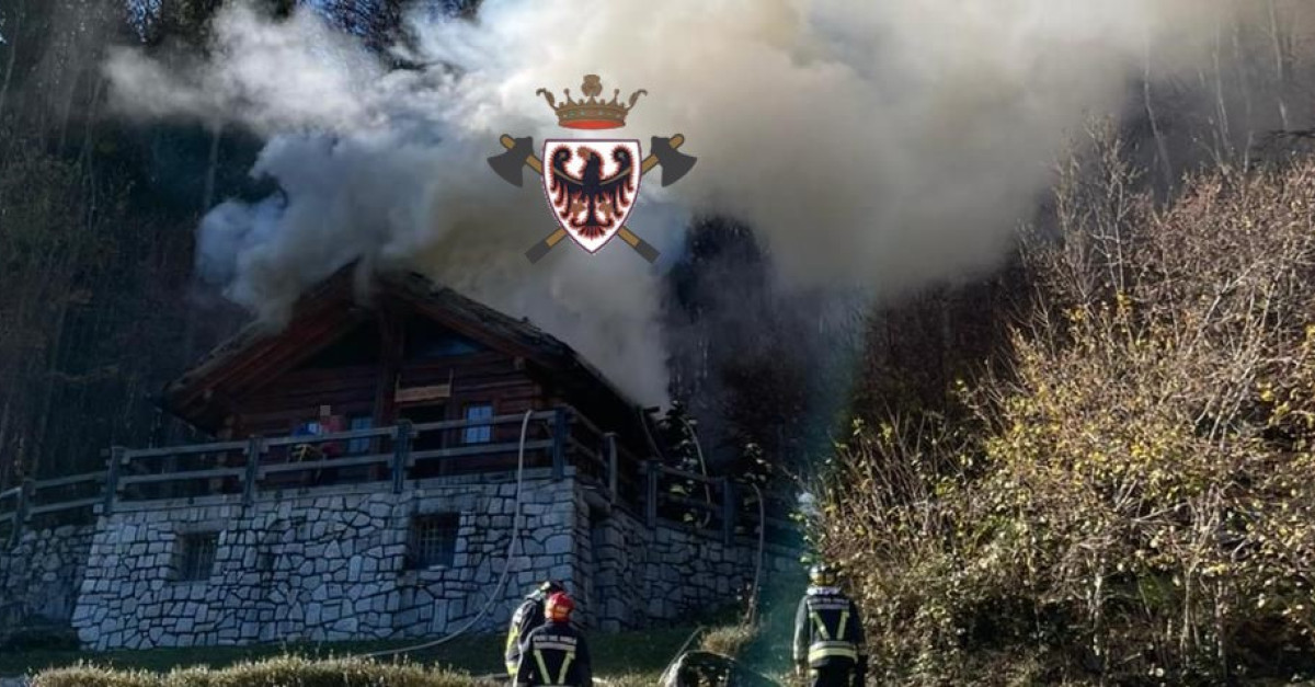 Fiamme dal tetto della baita e una colonna di fumo si alza in cielo ...