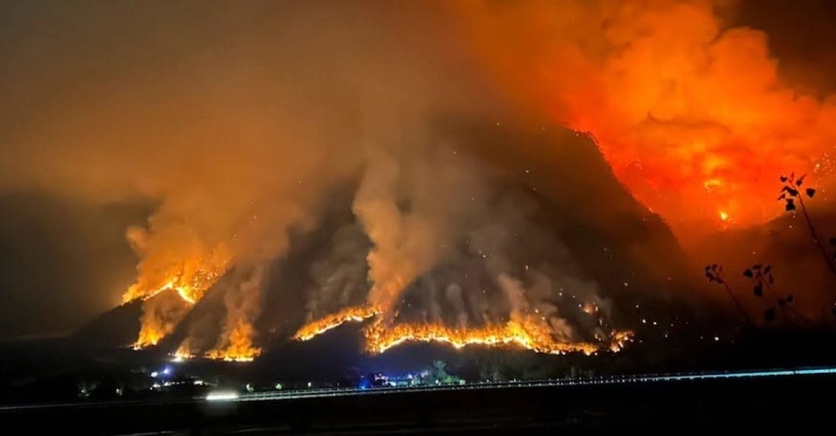 Montagna in fiamme, fumo e fiamme si diffondono nei boschi, vigili del fuoco al lavoro